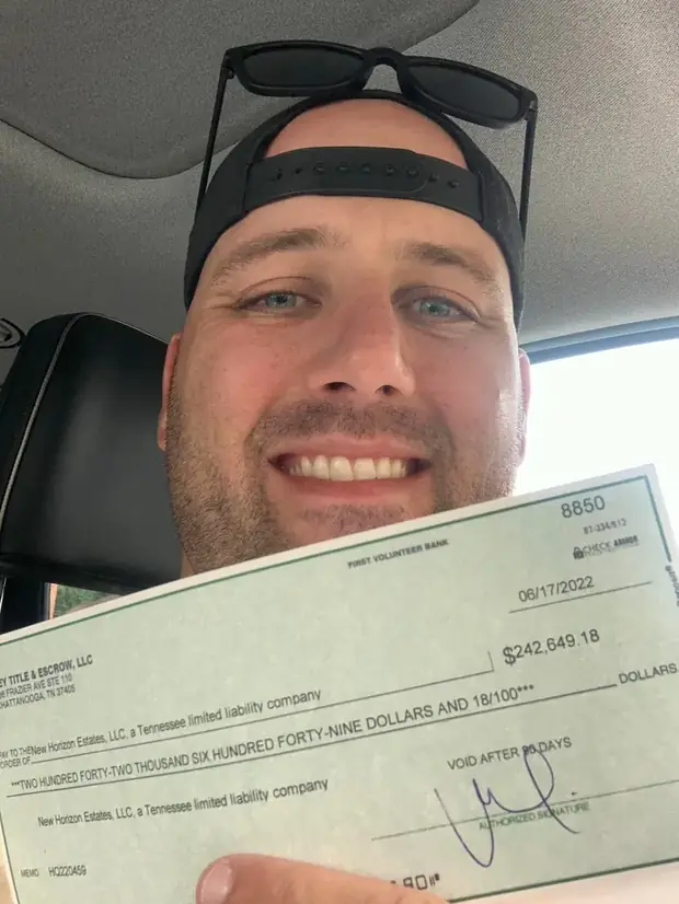Erik in his truck holding the closing check from the flip — First Volunteer Bank, 06/17/2022, $242,649.18, payable to New Horizon Estates, LLC.